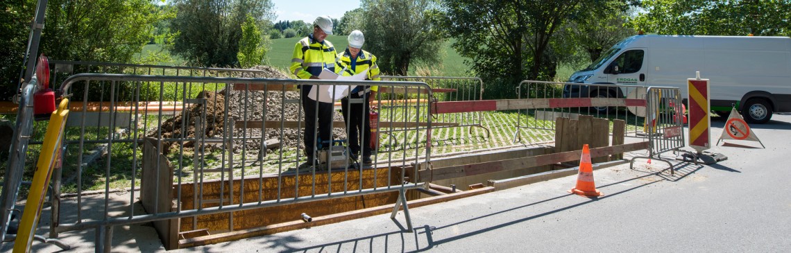 Außenaufnahem von zwei Mitarbeitern, die sich auf sich auf der Baustelle besprechen.