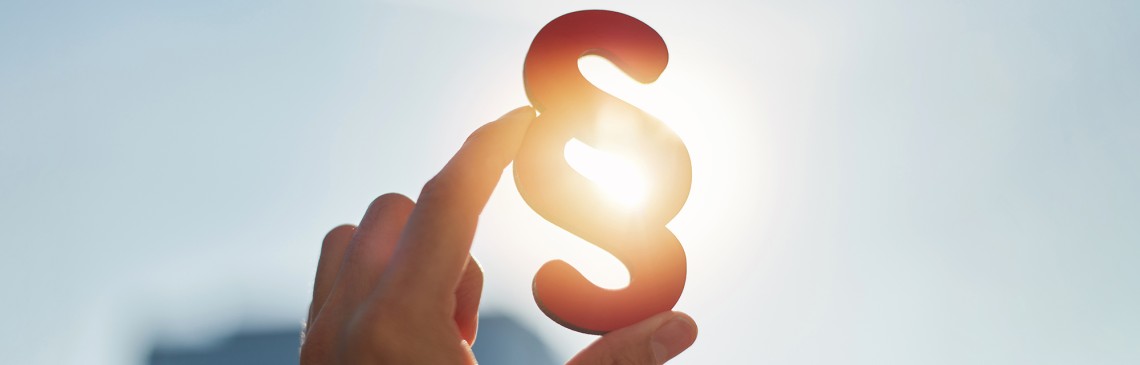 Hand hält Paragraphen Zeichen in die Sonne