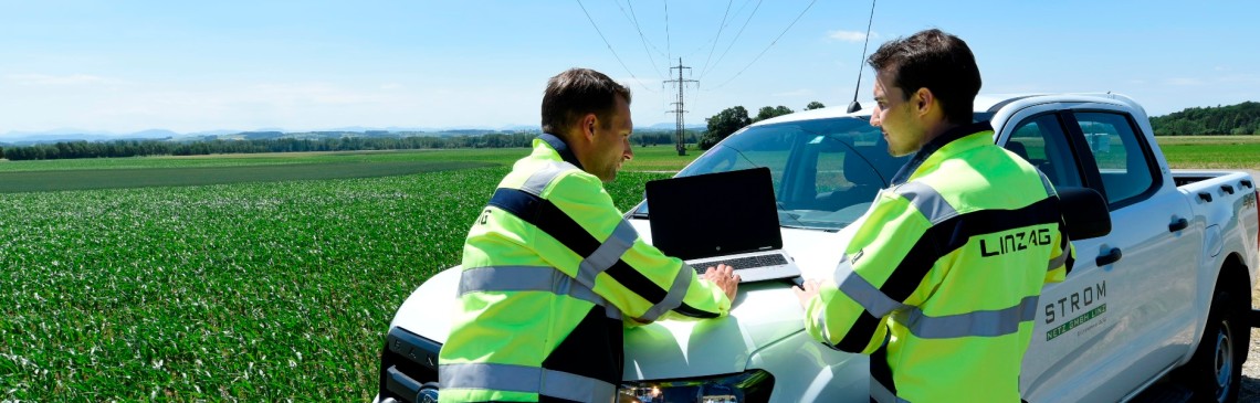 Zwei Mitarbeiter besprechen sich auf der Motorhaube eines Pick-ups.