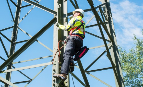 Ein Mitarbeiter klettert auf einen Strommast.