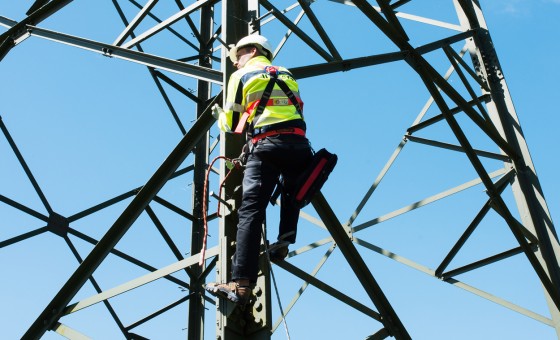 Ein Mitarbeiter klettert auf einen Strommast.